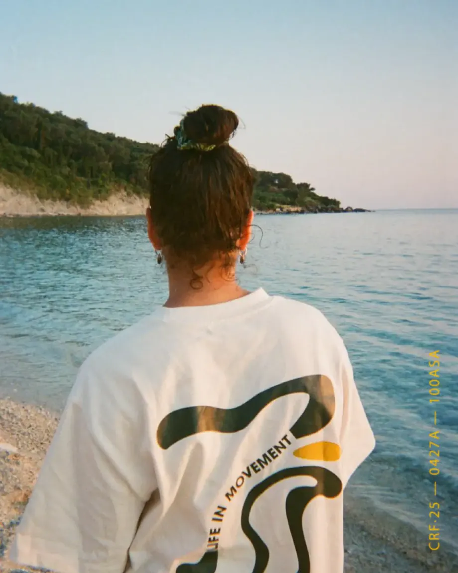 Woman by the sea wearing the T-shirt, its wave print on the back