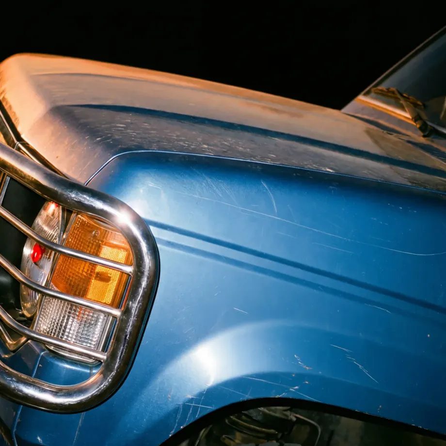 Close-up of a blue four-by-four's headlight and grille bar at night