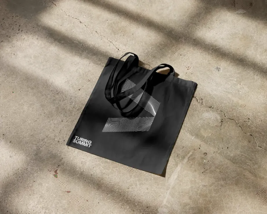 Black Turing Summit tote bag on a sunlit concrete floor